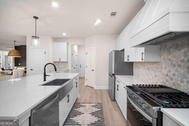 kitchen with visible vents, light wood-style floors, custom range hood, a sink, and appliances with stainless steel finishes