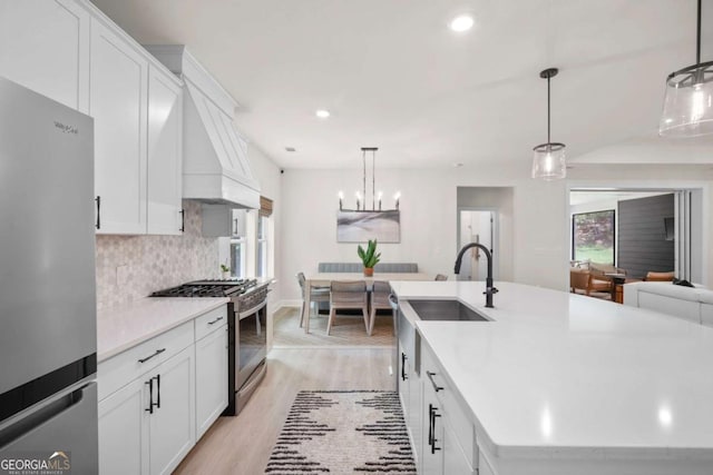 kitchen featuring appliances with stainless steel finishes, tasteful backsplash, light wood-type flooring, light countertops, and custom range hood