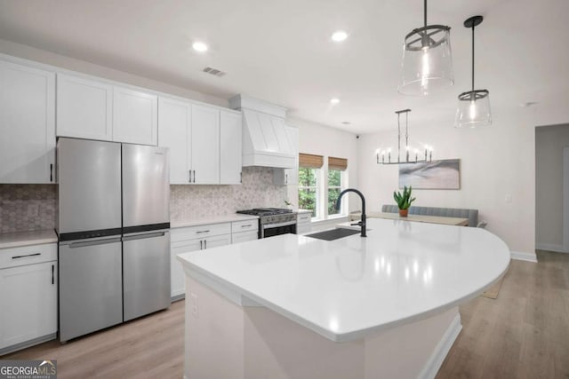 kitchen featuring visible vents, appliances with stainless steel finishes, a sink, custom exhaust hood, and light wood-style flooring