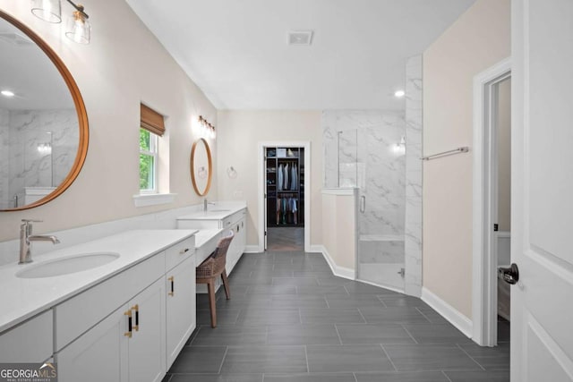 full bathroom featuring two vanities, baseboards, a marble finish shower, and a sink