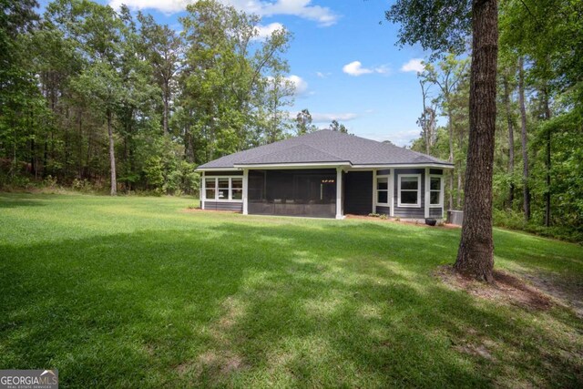 back of property with roof with shingles, a yard, and a sunroom