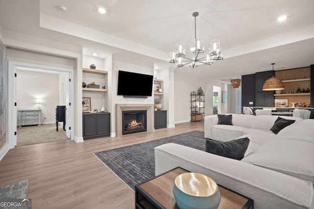 living room featuring baseboards, built in shelves, and light wood-type flooring