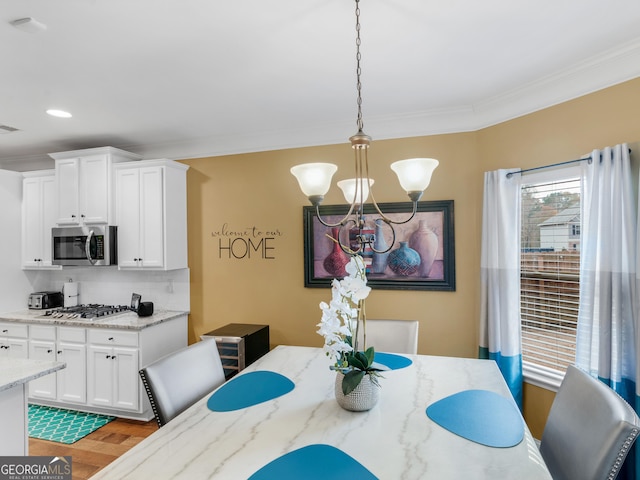 dining area with ornamental molding, a toaster, light wood-style floors, recessed lighting, and a chandelier