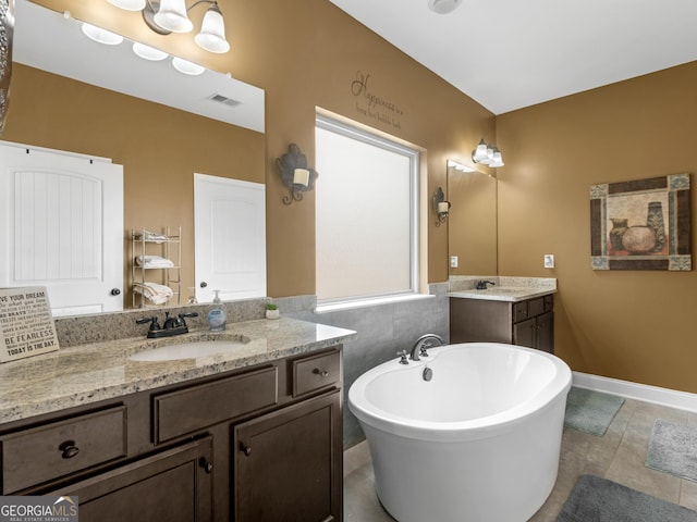 bathroom featuring a sink, tile patterned flooring, two vanities, visible vents, and a soaking tub