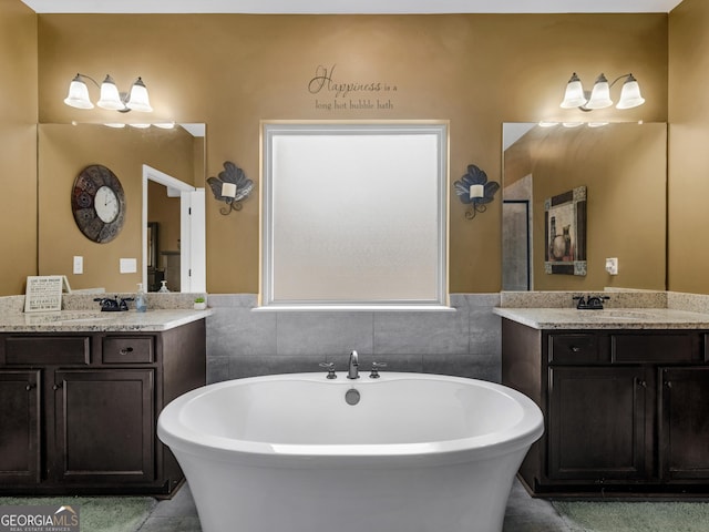 bathroom featuring a freestanding bath, two vanities, and a sink