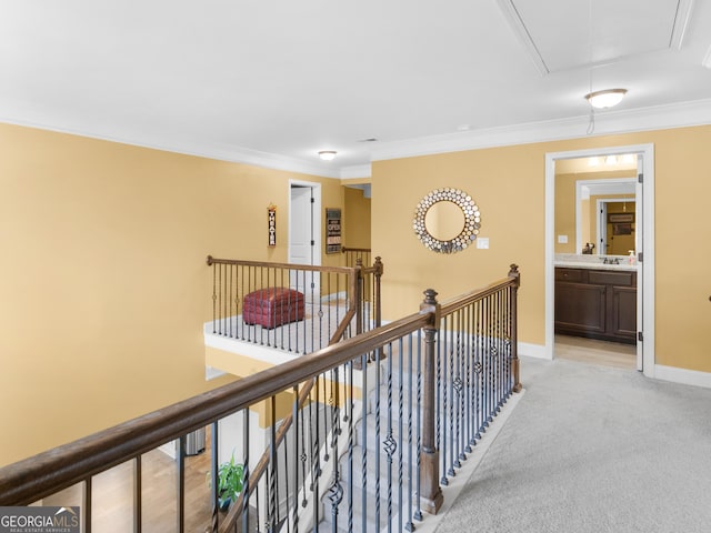 corridor with ornamental molding, light carpet, baseboards, attic access, and an upstairs landing