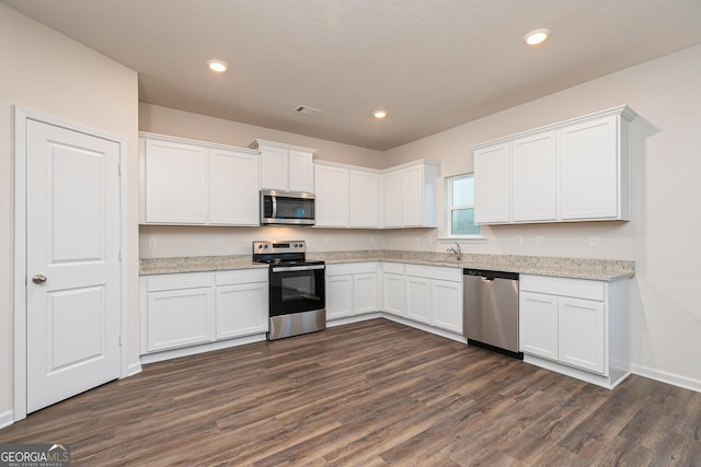 244 Oliver Dr, Locust Grove, GA 30248 - kitchen with appliances with stainless steel finishes, light stone countertops, a sink, dark wood-style floors, and white cabinetry