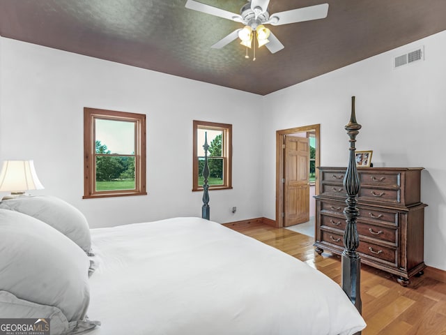 bedroom with baseboards, ceiling fan, light wood finished floors, and visible vents
