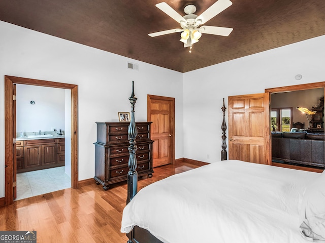 bedroom with baseboards, visible vents, a sink, and light wood-style floors