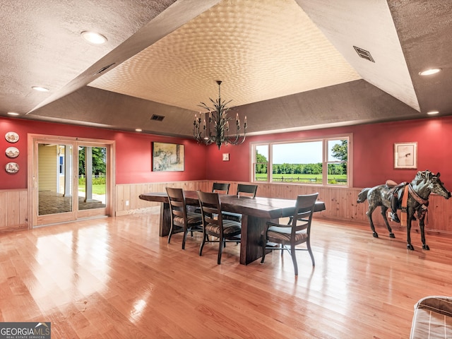dining room with wainscoting, a tray ceiling, and wood finished floors
