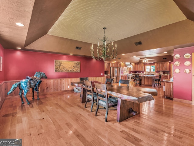dining area featuring visible vents, light wood-style flooring, and a tray ceiling