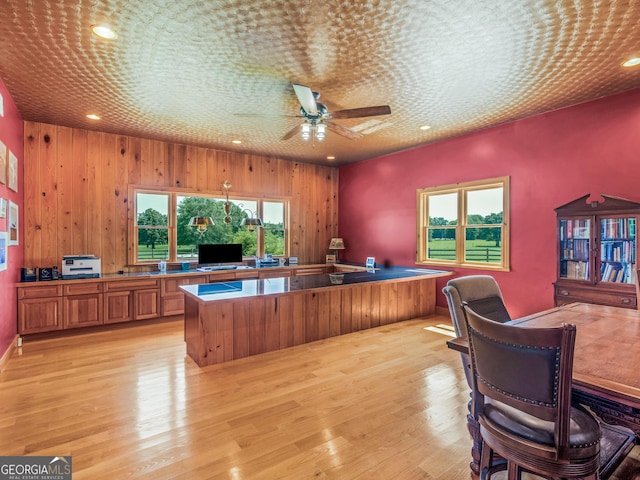 office area with light wood-style floors, recessed lighting, ceiling fan, and wooden walls