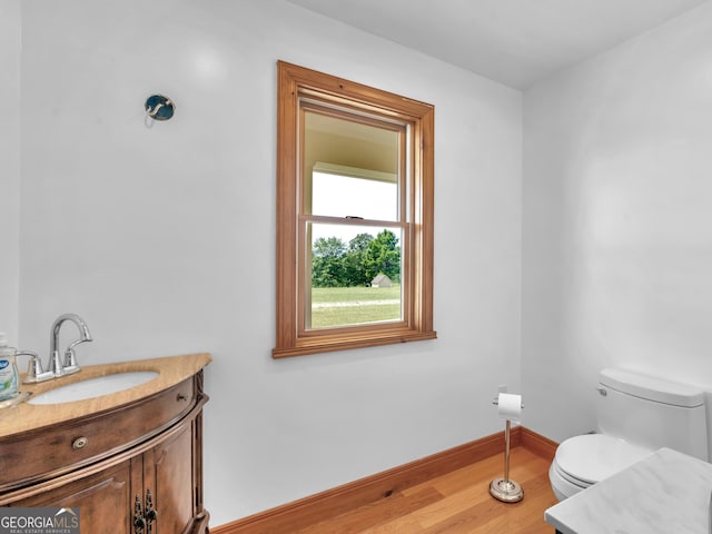 bathroom with vanity, baseboards, wood finished floors, and toilet