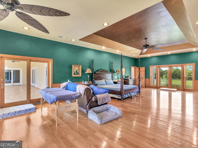 bedroom with french doors, recessed lighting, wood finished floors, a tray ceiling, and visible vents