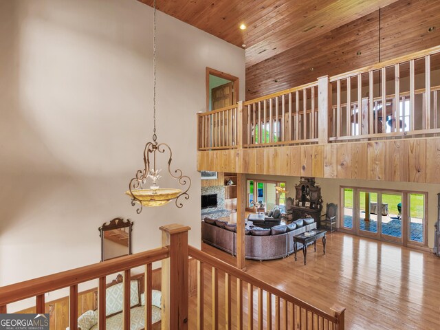 living room featuring a healthy amount of sunlight, wood ceiling, wood finished floors, and a towering ceiling