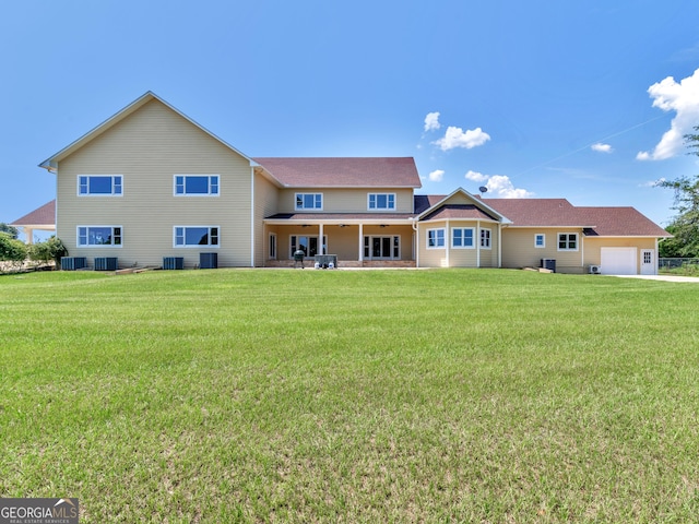 rear view of property featuring a yard, central AC, and a garage