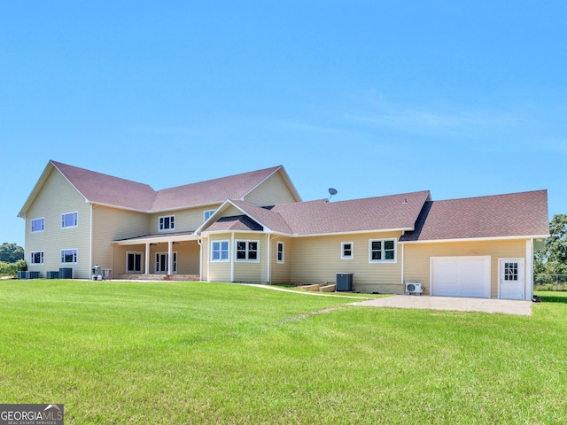 back of property featuring a lawn, a garage, and central air condition unit