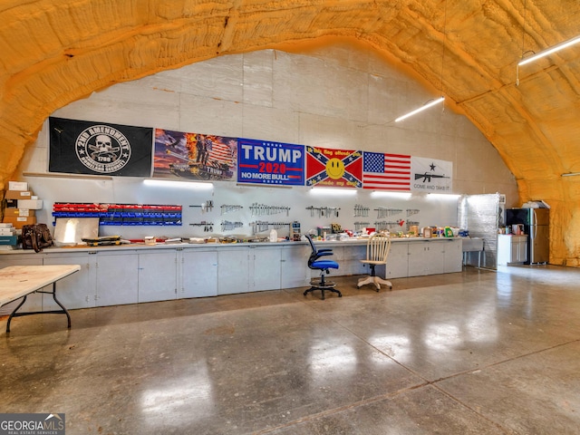 miscellaneous room with concrete flooring, lofted ceiling, and a workshop area