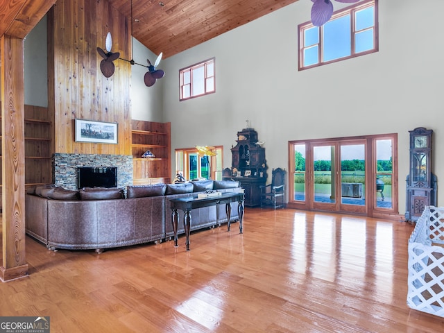 living area featuring a stone fireplace, wood ceiling, wood finished floors, and high vaulted ceiling