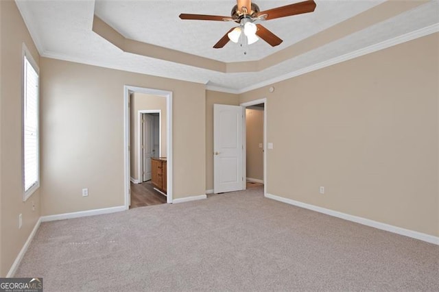 145 Tara Way, Covington, GA 30016 - unfurnished bedroom featuring carpet flooring, a tray ceiling, crown molding, ensuite bath, and ceiling fan