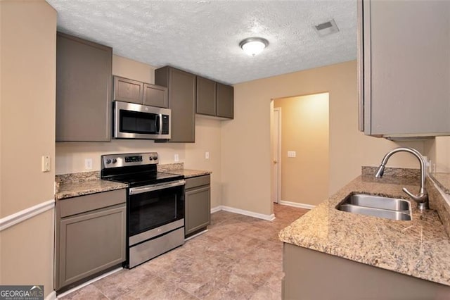 145 Tara Way, Covington, GA 30016 - kitchen with appliances with stainless steel finishes, a textured ceiling, light stone counters, and gray cabinets