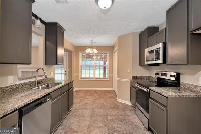145 Tara Way, Covington, GA 30016 - kitchen featuring stainless steel appliances, a chandelier, a textured ceiling, light stone counters, and hanging light fixtures
