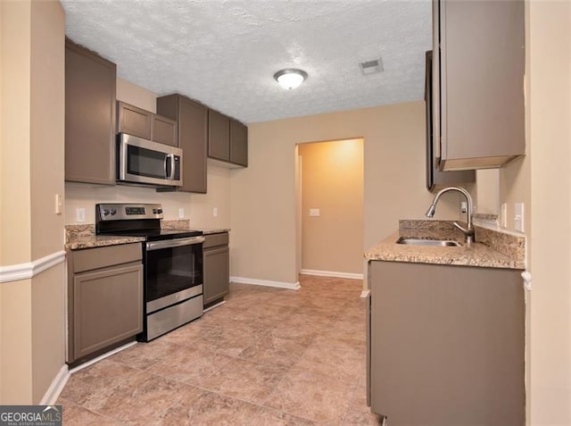 145 Tara Way, Covington, GA 30016 - kitchen featuring stainless steel appliances, a textured ceiling, and light stone countertops