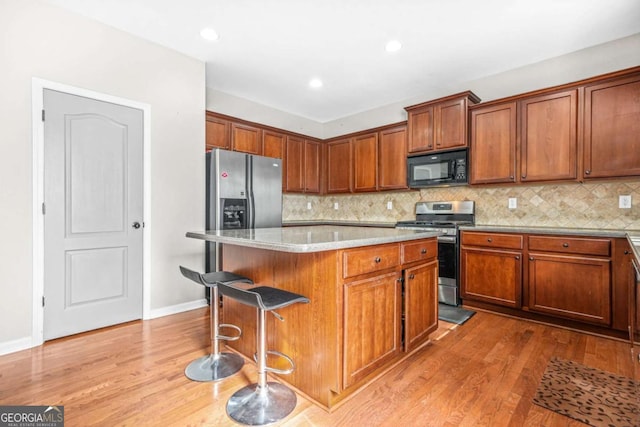 kitchen featuring a center island, wood finished floors, a kitchen bar, and stainless steel appliances