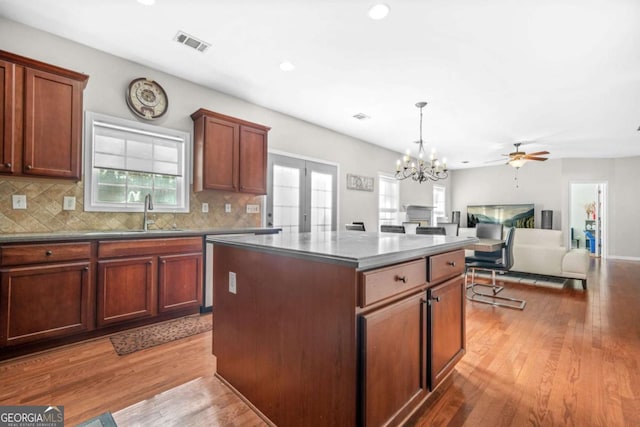kitchen featuring a sink, wood-type flooring, tasteful backsplash, a kitchen island, and visible vents