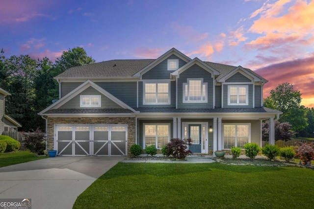 craftsman house featuring roof with shingles, a yard, concrete driveway, and stone siding