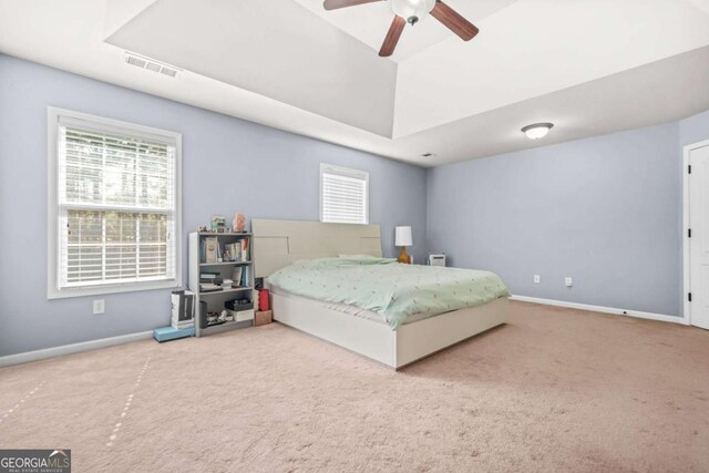 bedroom featuring visible vents, carpet, baseboards, and a tray ceiling