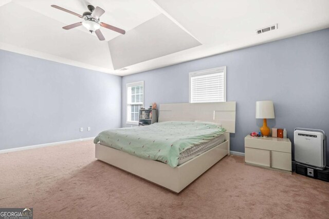 carpeted bedroom featuring baseboards, ceiling fan, a tray ceiling, and visible vents