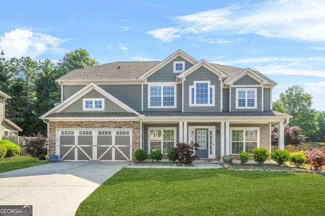 craftsman house with a garage, a front lawn, driveway, and stone siding