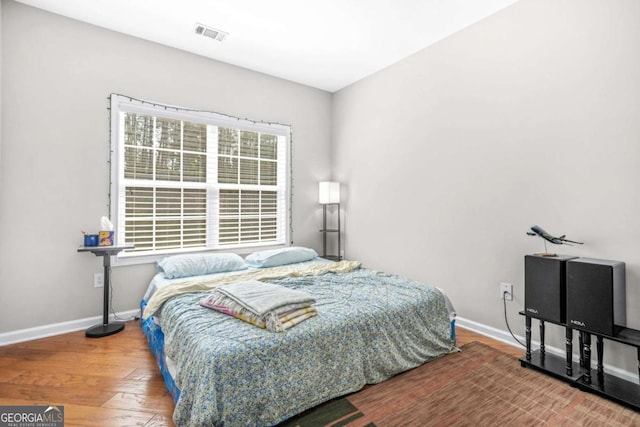 bedroom with visible vents, baseboards, and wood finished floors