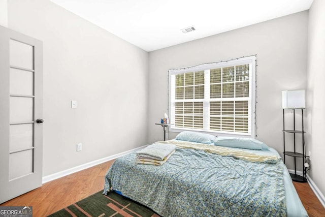 bedroom with baseboards, wood finished floors, and visible vents