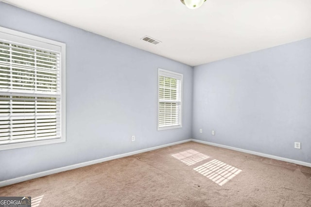 carpeted spare room featuring baseboards and visible vents