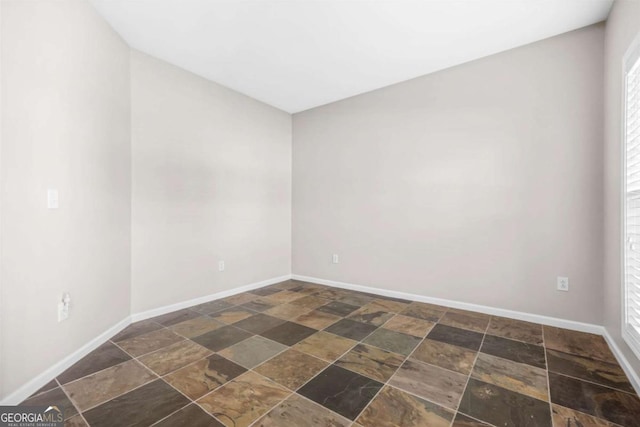 empty room with stone tile flooring and baseboards