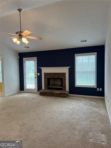 3218 Watson Woods Way, Loganville, GA 30052 - unfurnished living room featuring a fireplace, carpet floors, a ceiling fan, baseboards, and visible vents
