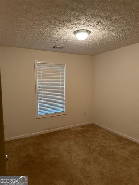 3218 Watson Woods Way, Loganville, GA 30052 - unfurnished living room featuring a fireplace, carpet floors, a ceiling fan, baseboards, and visible vents
