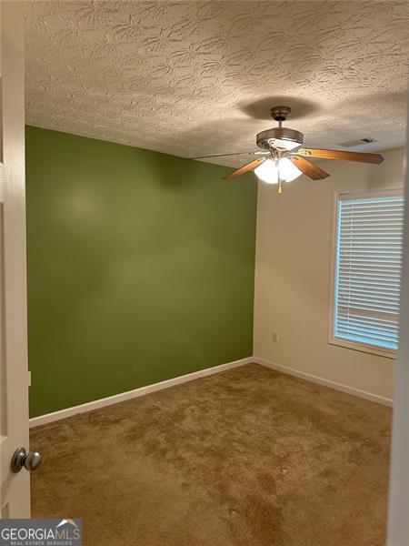 3218 Watson Woods Way, Loganville, GA 30052 - spare room featuring a ceiling fan, a textured ceiling, visible vents, baseboards, and carpet flooring