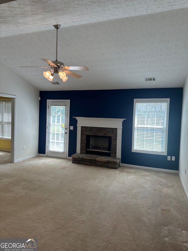 3218 Watson Woods Way, Loganville, GA 30052 - unfurnished living room featuring carpet floors, a ceiling fan, a stone fireplace, and visible vents