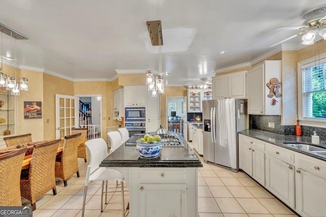 kitchen with a ceiling fan, a kitchen bar, a center island, stainless steel appliances, and light tile patterned flooring