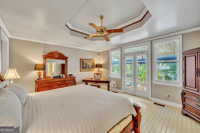 bedroom featuring baseboards, light wood finished floors, a tray ceiling, and access to exterior