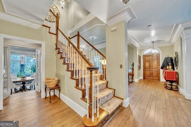 foyer with crown molding, baseboards, light wood-type flooring, and stairs