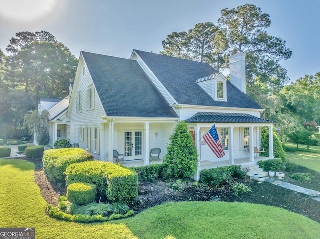 exterior space featuring a porch, french doors, a front lawn, and a chimney