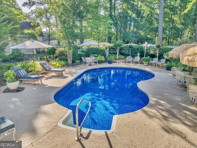 pool with outdoor dining area and a patio area