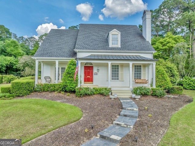 view of front facade with a standing seam roof, covered porch, a shingled roof, and metal roof