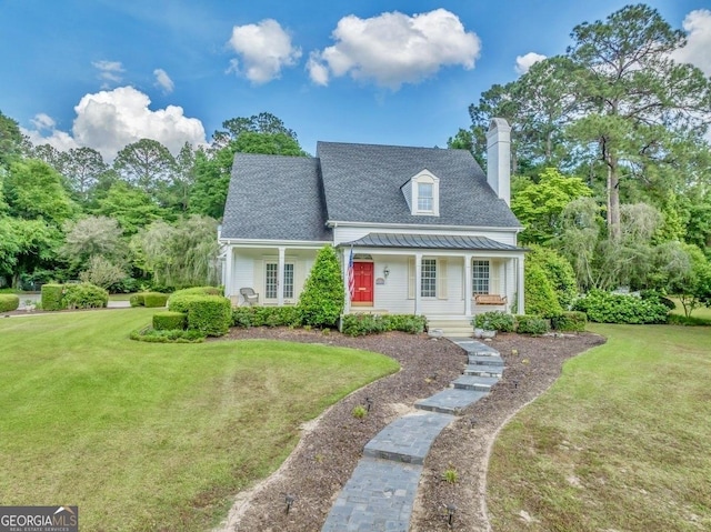 cape cod home featuring a standing seam roof, covered porch, a chimney, and a front yard