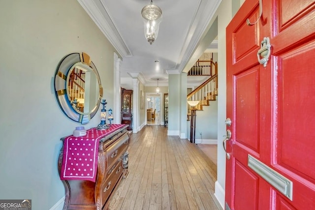 foyer entrance with crown molding, stairway, baseboards, light wood finished floors, and ornate columns