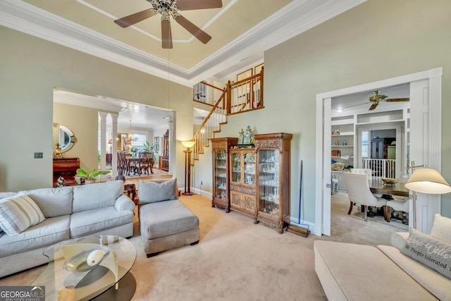 carpeted living room with crown molding, stairway, ceiling fan with notable chandelier, and a towering ceiling